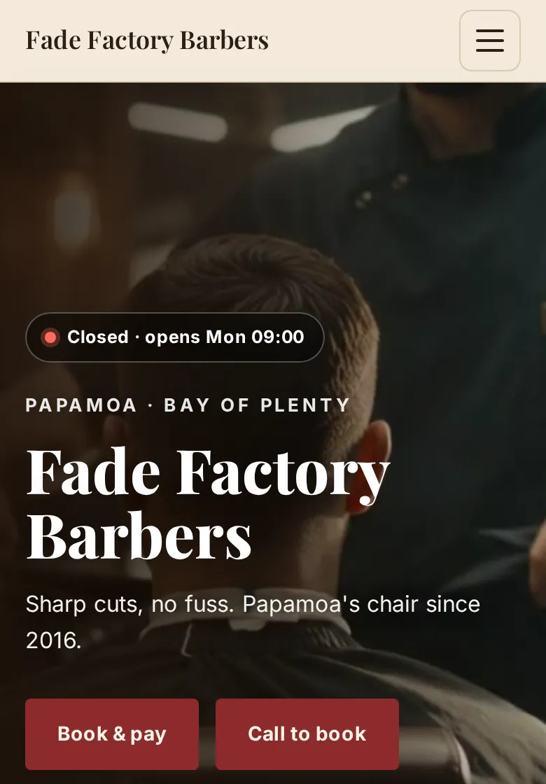 Heritage style barbershop website on a phone: cream header, serif shop name and deep red buttons